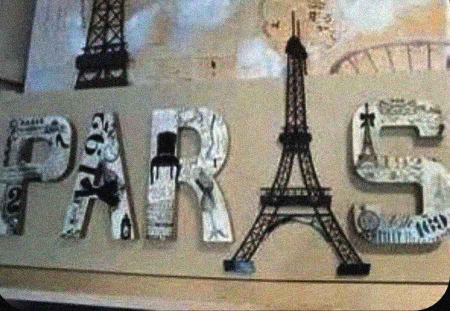 The word "PARIS" is spelled out with decorated letters; the letter "I" is replaced by an illustration of the Eiffel Tower. The letters feature various black and white Paris-themed designs.