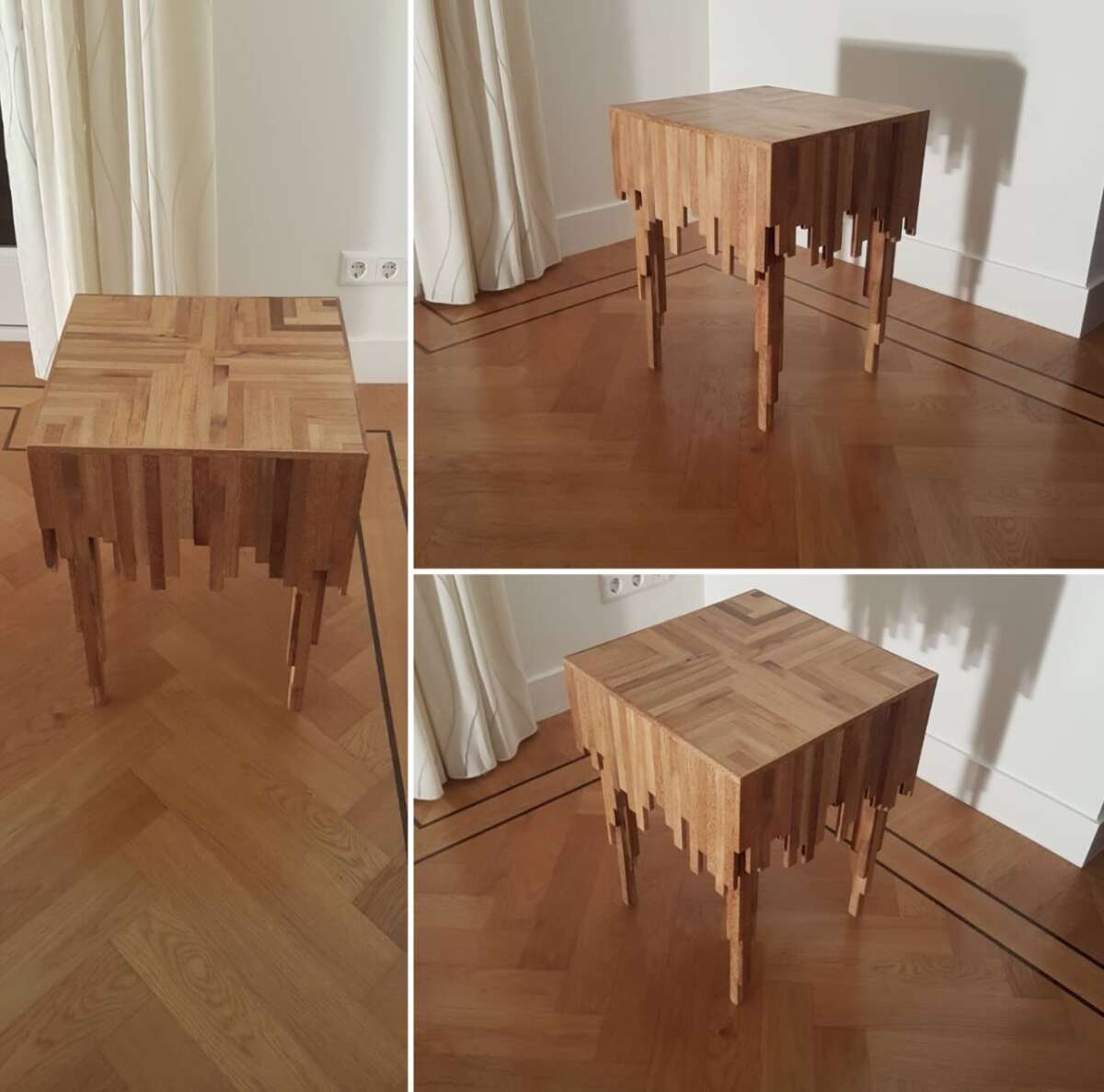A wooden table with a unique design, featuring straight edges on top and legs that appear to “drip” downward in uneven lengths, creating a melting optical illusion. The table is set on a hardwood floor near white curtains.