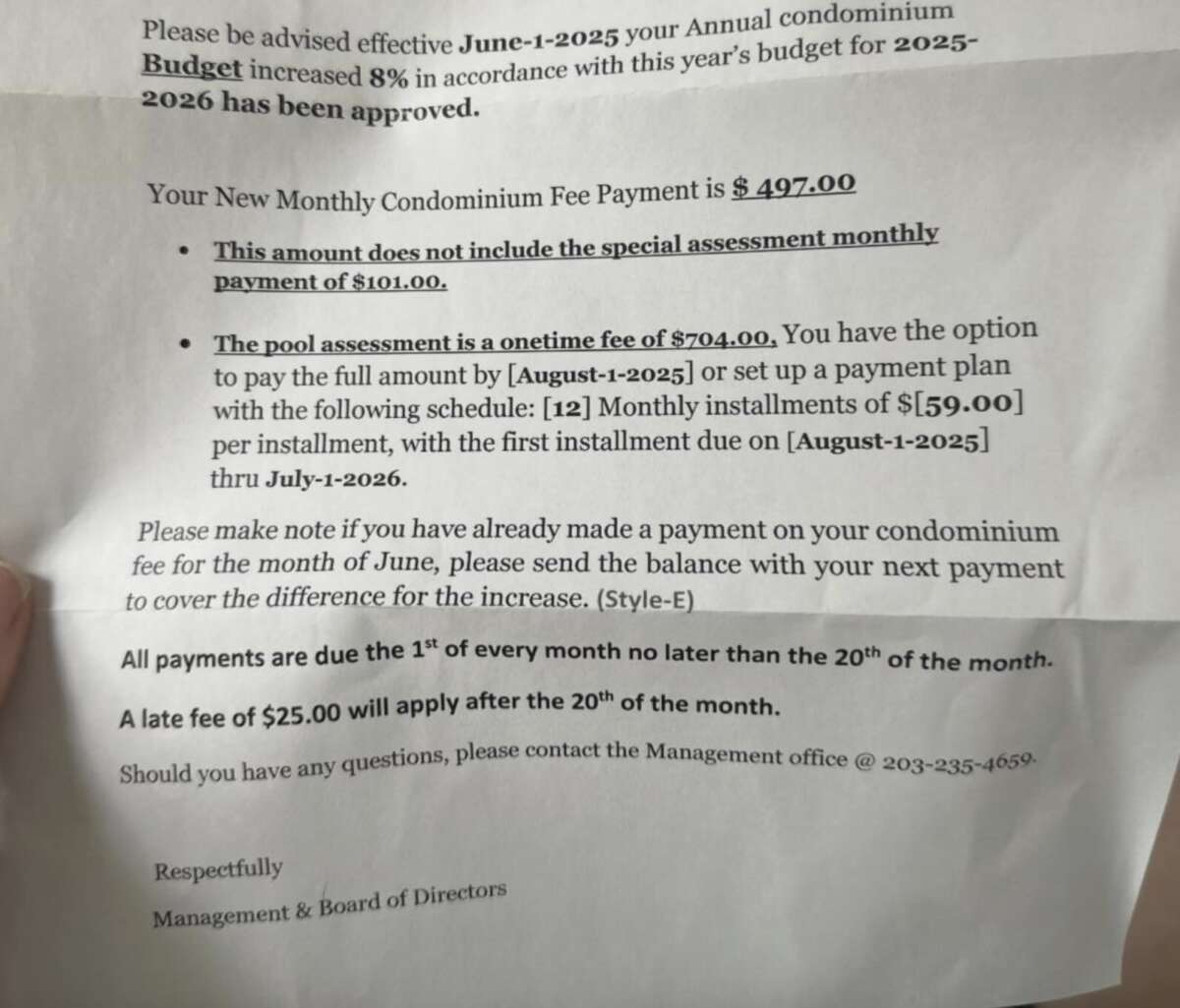 A hand holds a letter detailing new condominium payment fees, including a monthly fee of $497, a special assessment fee, installment options, a late fee, and contact information for the Management & Board of Directors.