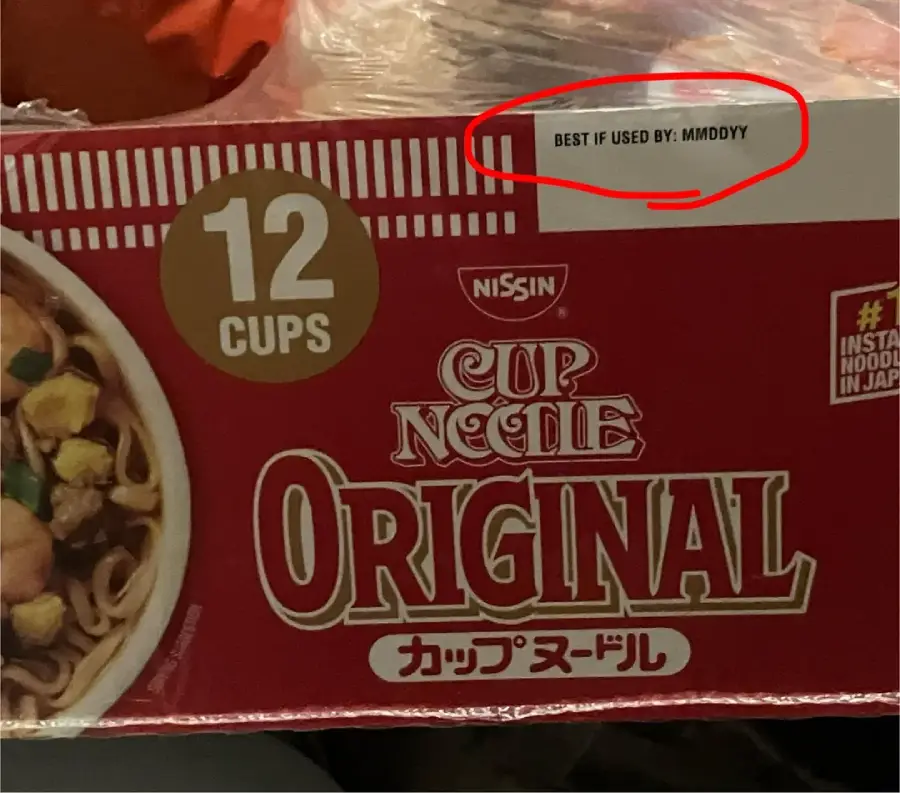 A 12-cup pack of Nissin Cup Noodle Original with a red box. A label in the corner says “BEST IF USED BY: MMDDYY,” with a red circle drawn around it.
