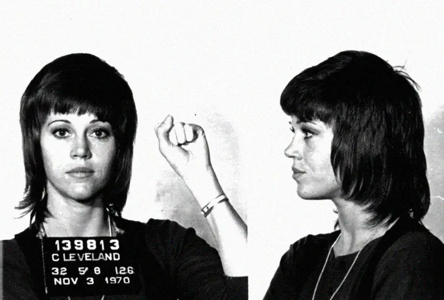 Black-and-white mugshot of a woman with short, dark hair raising a clenched fist in one photo and shown in profile in the other. A placard displays "CLEVELAND" and the date November 3, 1970.