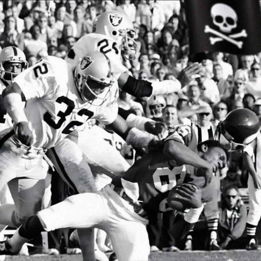 A football player in a dark uniform is tackled by two opponents in light uniforms during a game, as a crowd watches. One tackler grabs the ball carrier's facemask. A pirate flag is visible in the background.