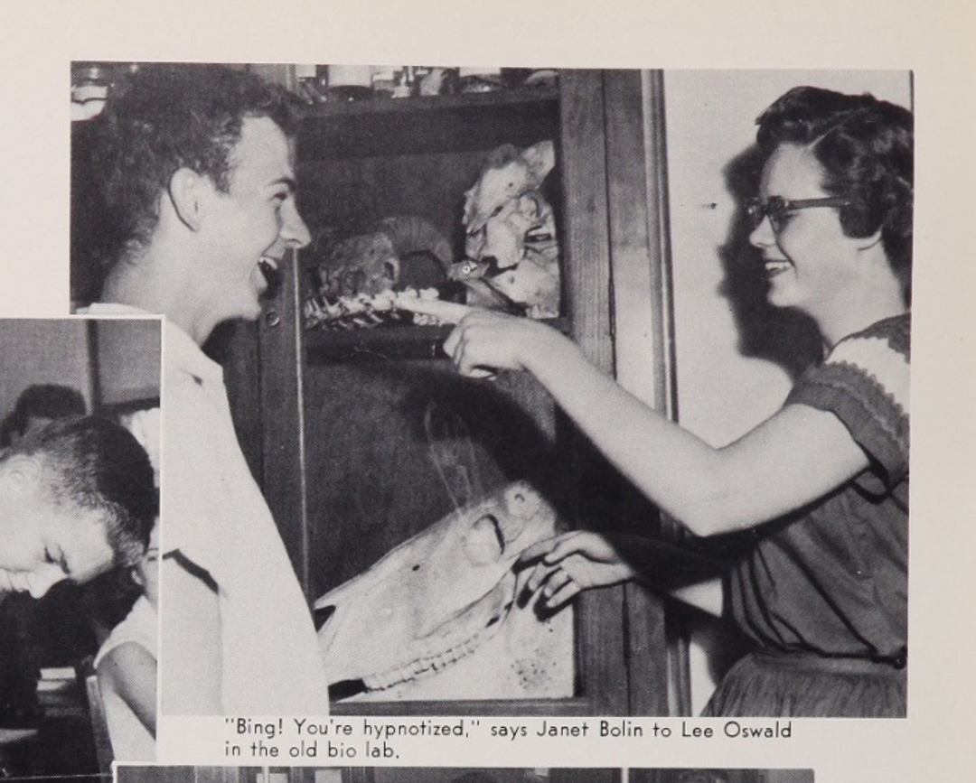 A young woman playfully points at a smiling young man in front of a cabinet filled with animal specimens. Caption reads: "'Bing! You're hypnotized,' says Janet Bolin to Lee Oswald in the old bio lab.