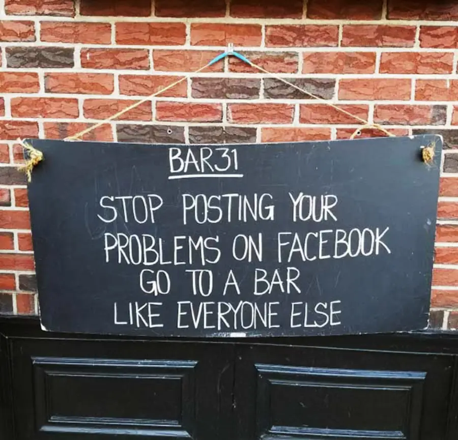 A chalkboard sign mounted on a brick wall outside Bar 31 reads: "STOP POSTING YOUR PROBLEMS ON FACEBOOK. GO TO A BAR LIKE EVERYONE ELSE.