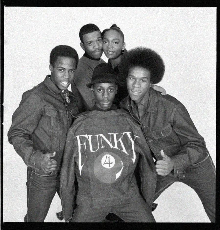 Five people pose together in denim outfits, with one person in front wearing a jacket that says "FUNKY 4." They smile and stand closely, facing the camera against a plain background.