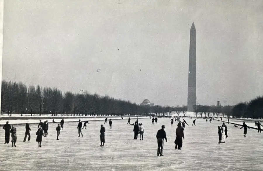 People ice skating on a frozen Reflecting Pool in Washington, D.C., with the Washington Monument and trees visible in the background on a winter day.