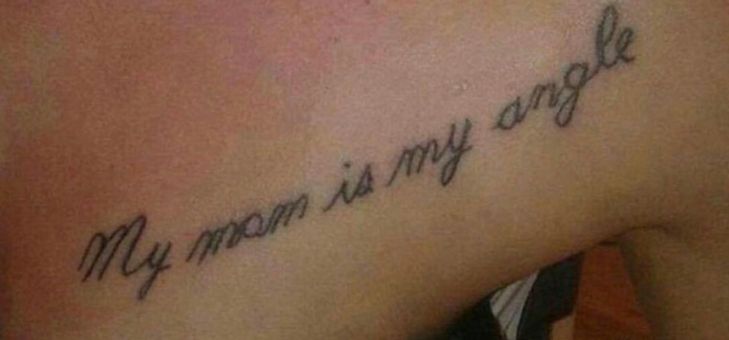 A tattoo in cursive handwriting on a person's upper chest reads "My mom is my angle," with a spelling mistake for "angel.