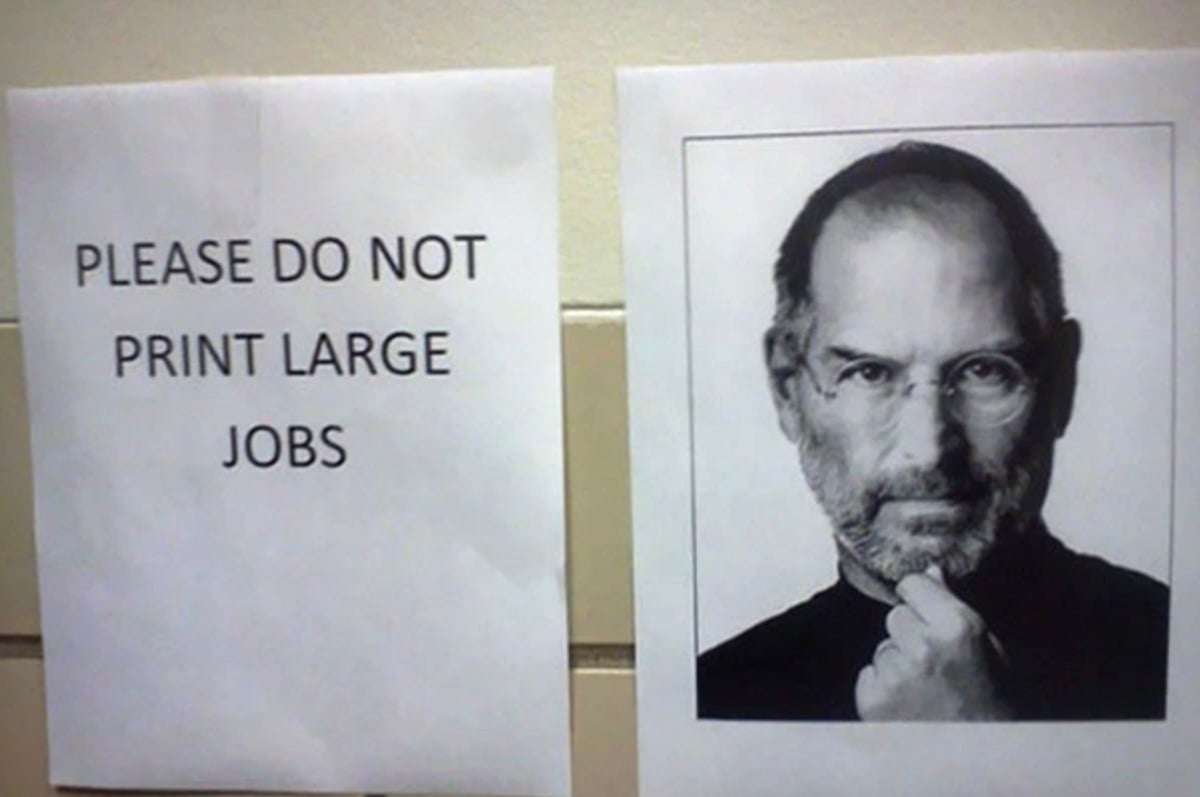 A printed sign reads "PLEASE DO NOT PRINT LARGE JOBS" next to a black-and-white photo of a man with glasses and a beard, resting his chin on his hand, implying a pun on his last name.