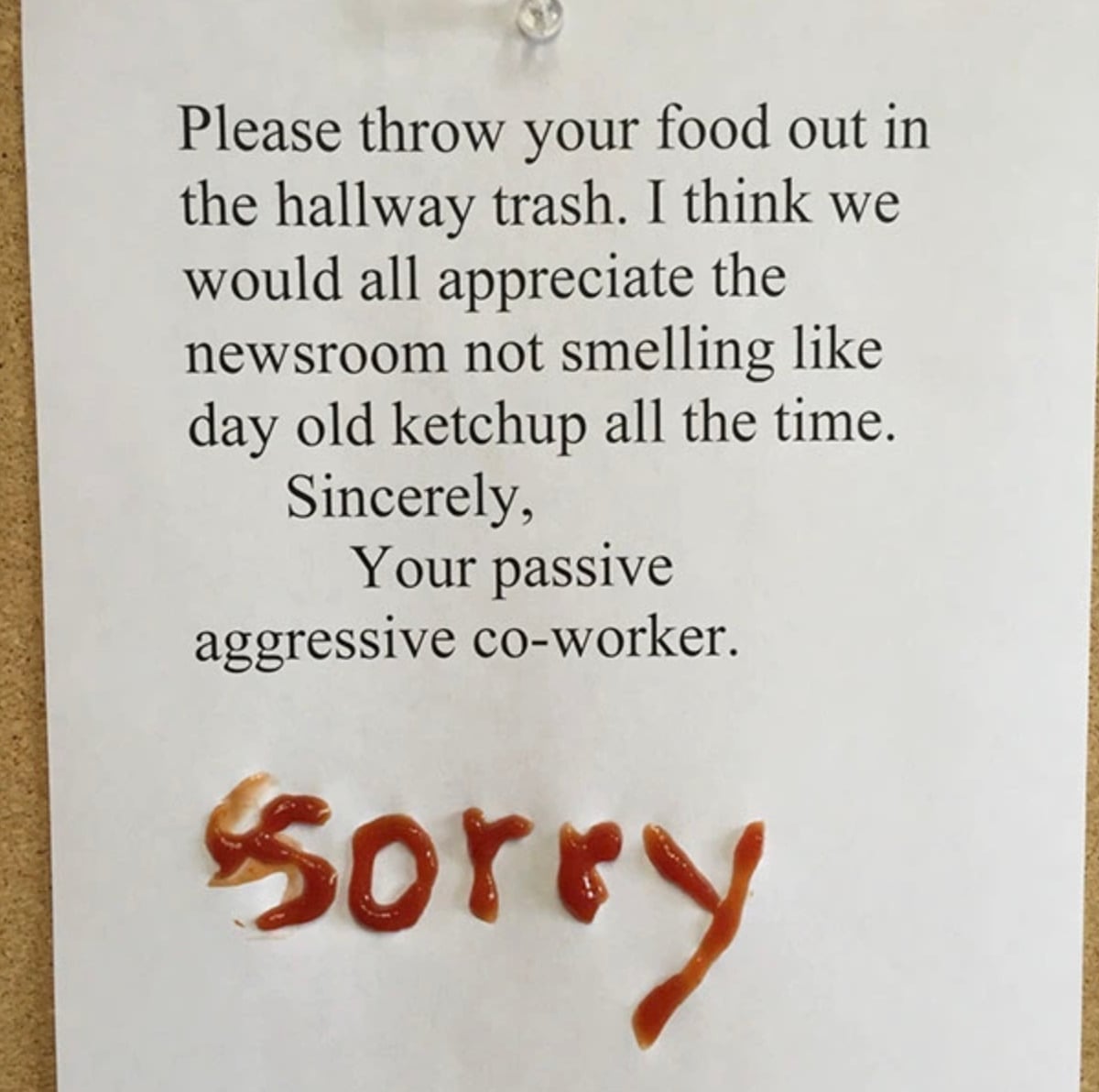 A printed note asks coworkers to throw out food elsewhere to avoid a newsroom smelling like old ketchup. The word "sorry" is written at the bottom in ketchup.
