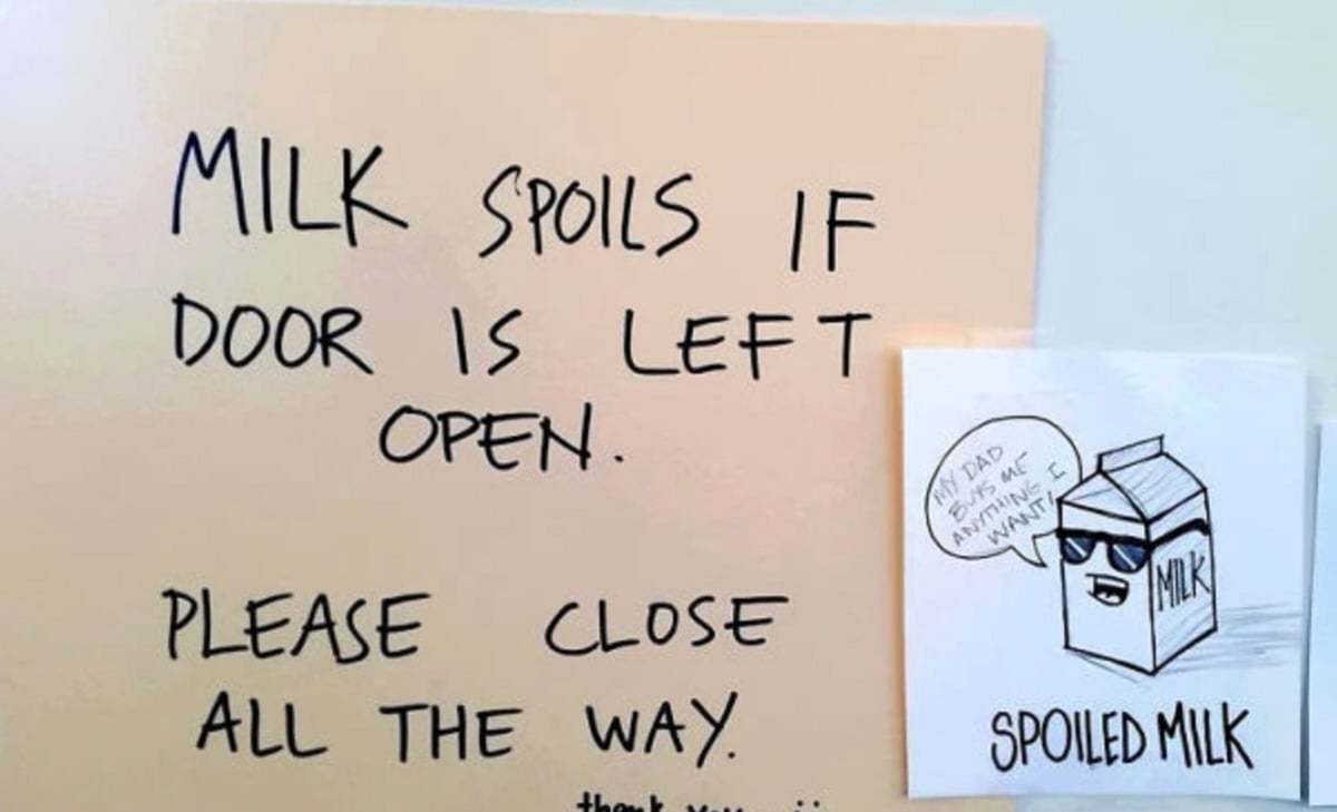 A handwritten sign says, "Milk spoils if door is left open. Please close all the way." Beside it, there's a cartoon milk carton labeled "Spoiled Milk," wearing sunglasses and saying, "My dad owns a fridge.