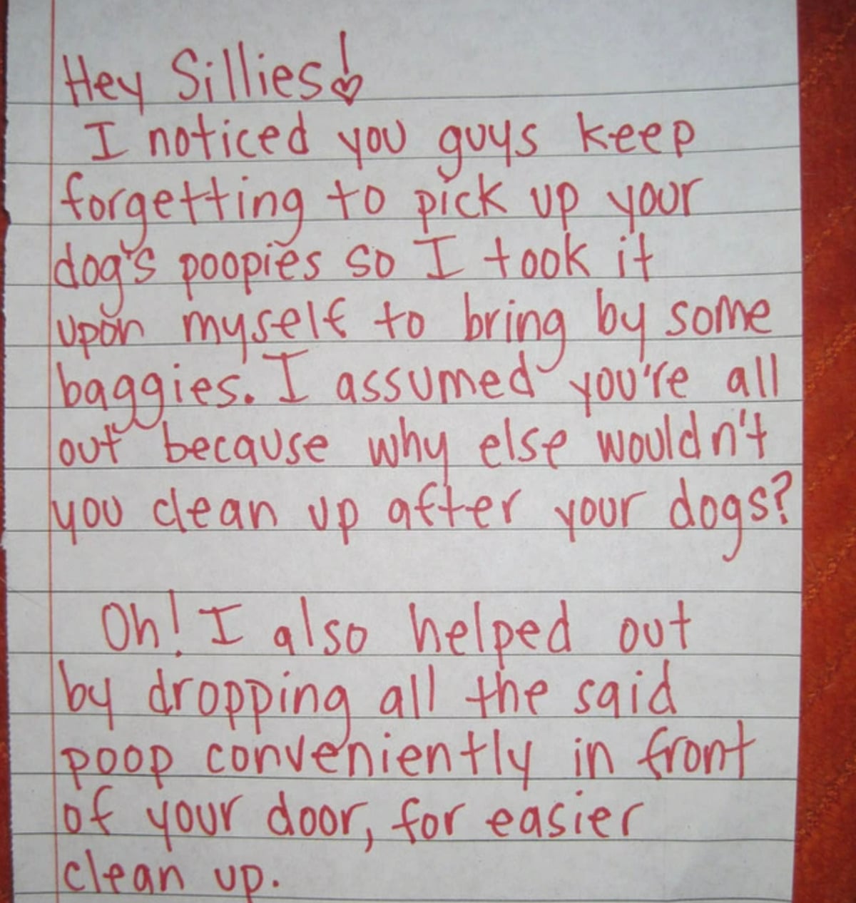 A handwritten note in red ink on white paper, asking neighbors to pick up their dogs' poop. The writer says they collected it in bags and left it by the recipient's door for easier cleanup.