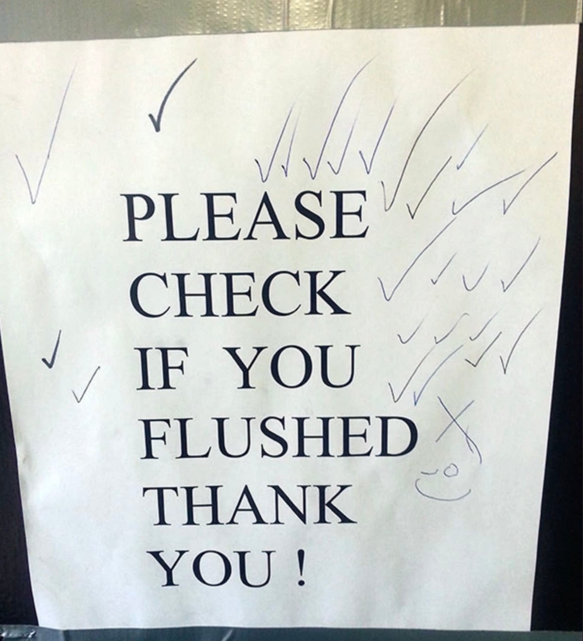 A sign reads "PLEASE CHECK IF YOU FLUSHED THANK YOU!" with handwritten check marks and a smiley face drawn in pen all over the paper.