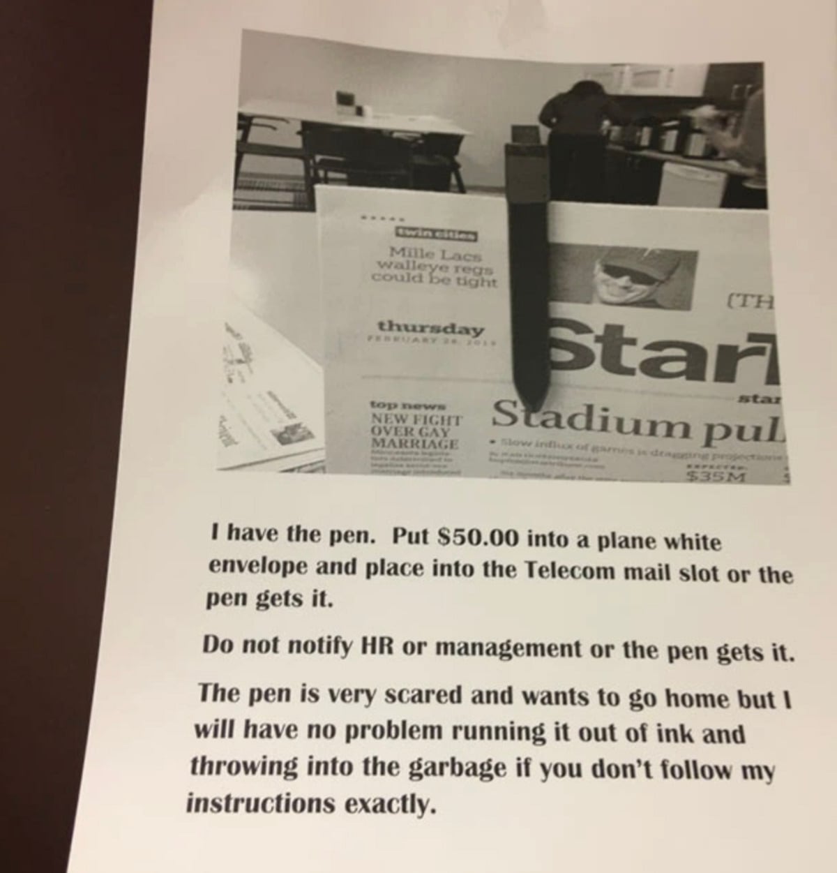 A printed ransom note with a photo of a newspaper, computer, and office background. The note demands $50 in an envelope and threatens to throw away a "scared" pen if instructions are not followed.
