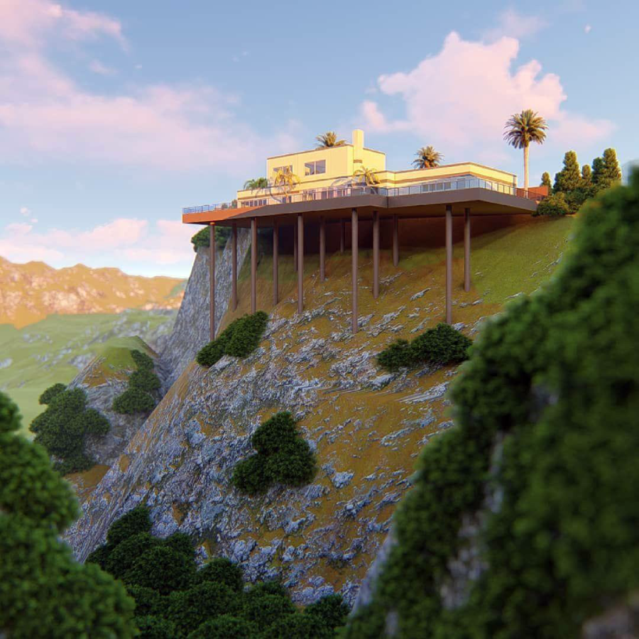 A modern house with large windows is perched on a steep mountainside, supported by tall stilts. The landscape is lush and green, with scattered trees and distant mountains under a partly cloudy sky.