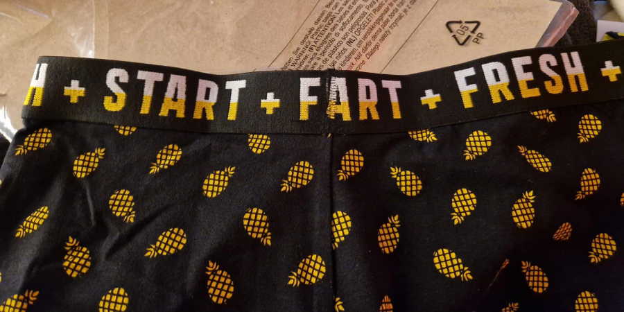A pair of black boxer briefs with yellow pineapple prints. The waistband reads "START FART FRESH" with each word separated by a plus sign.