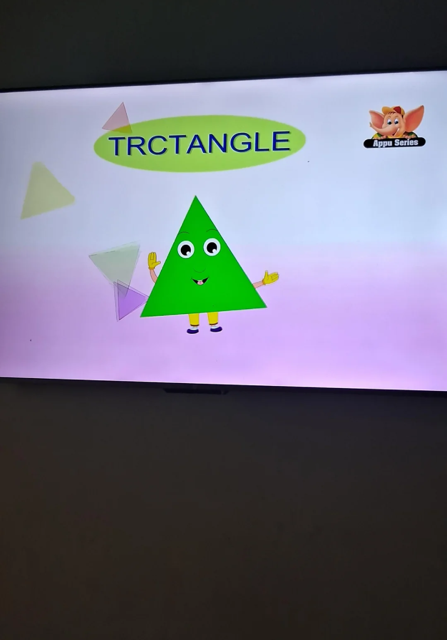A green cartoon triangle with eyes, mouth, hands, and shoes stands on a pink and white background under the misspelled word "TRCTANGLE." Colorful triangles and a logo appear in the corners.