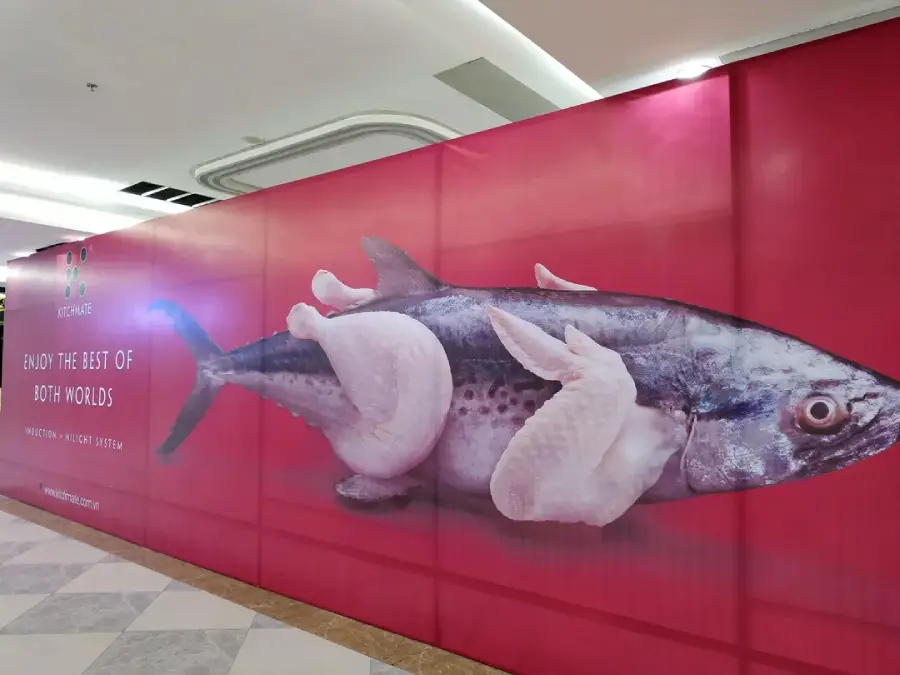 A large advertisement shows a creature with the body of a fish and chicken wings for fins against a red background, promoting a food fusion concept with the slogan “Enjoy the best of both worlds.”