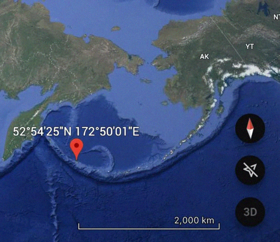 Satellite map view showing a red location marker in the Bering Sea near the Aleutian Islands, with coordinates 52°54'25"N 172°50'01"E. Compass and map tools are visible on the right. Alaska and part of Russia are shown.