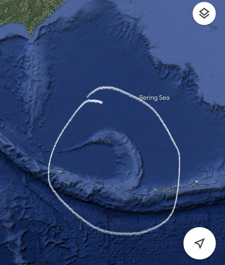 Satellite map view of the Bering Sea and the Aleutian Islands, with a large irregular white circle drawn around a crescent-shaped island chain in the ocean.