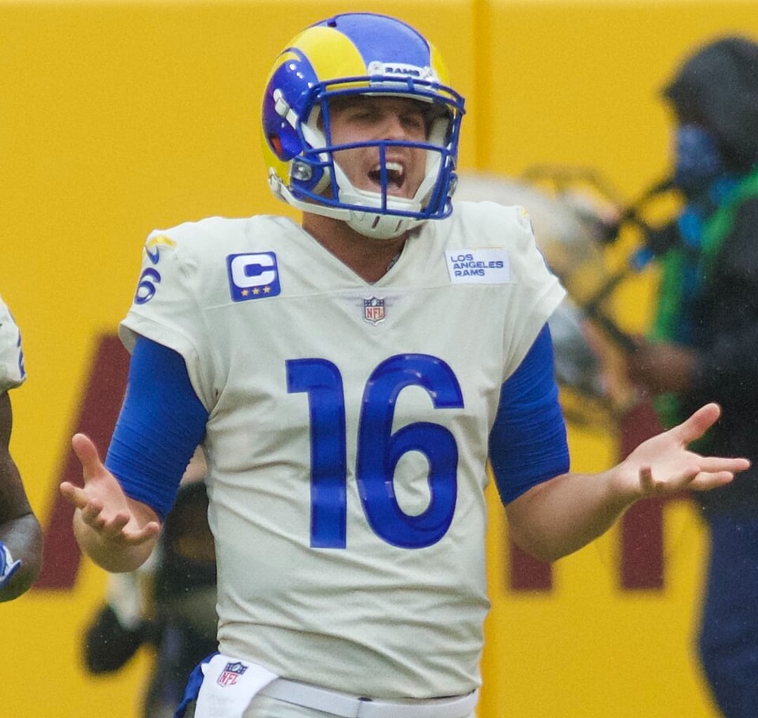 A Los Angeles Rams football player wearing a white and blue uniform with the number 16 gestures with his arms out and mouth open, appearing frustrated or confused during a game.