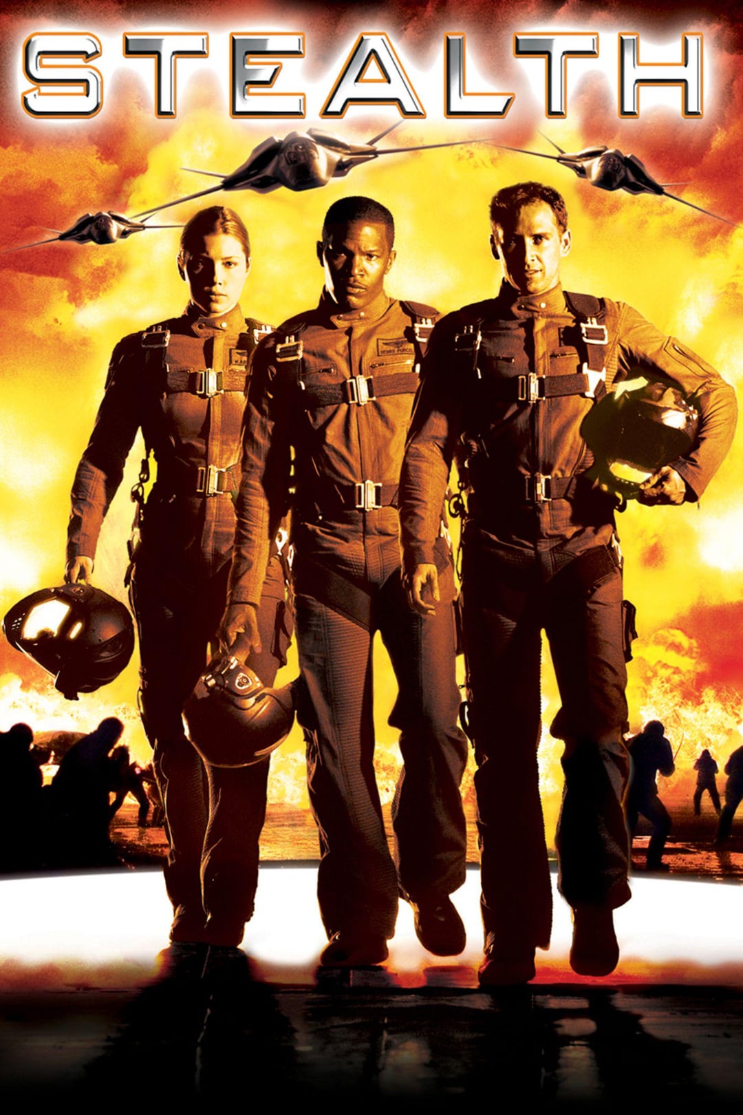Three pilots in brown flight suits and holding helmets walk toward the viewer against an orange and yellow fiery sky, with stealth jets flying overhead and silhouettes of people and planes in the background. The word "STEALTH" is at the top.