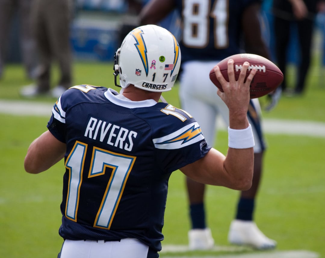 A football player wearing a Chargers uniform with the name "Rivers" and number 17 on the back prepares to throw a football during a game. Another player is visible in the background.