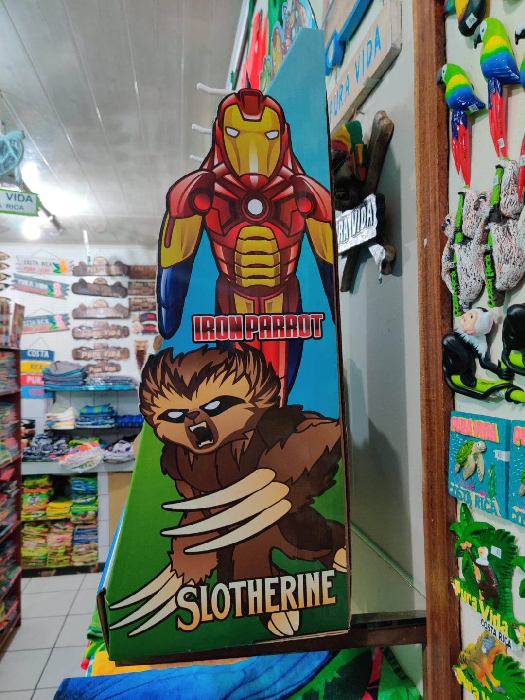 A colorful store display features cartoon mashups: "Iron Parrot," a parrot in Iron Man armor, and "Slotherine," a sloth with Wolverine-style claws. Various toys and items are visible in the background.