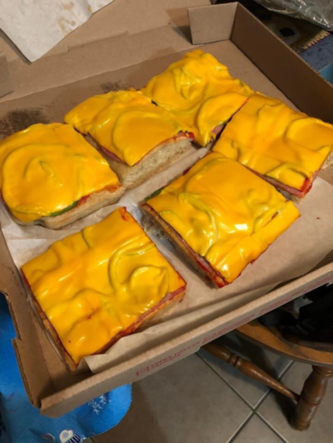 A box of sandwiches with yellow cheese