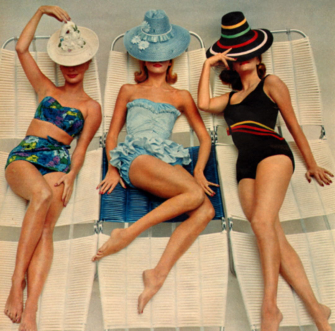 Three women in vintage swimsuits and wide-brimmed hats lounge on white chairs. Their faces are partially covered by their hats, and they pose stylishly, evoking a retro summer fashion vibe.