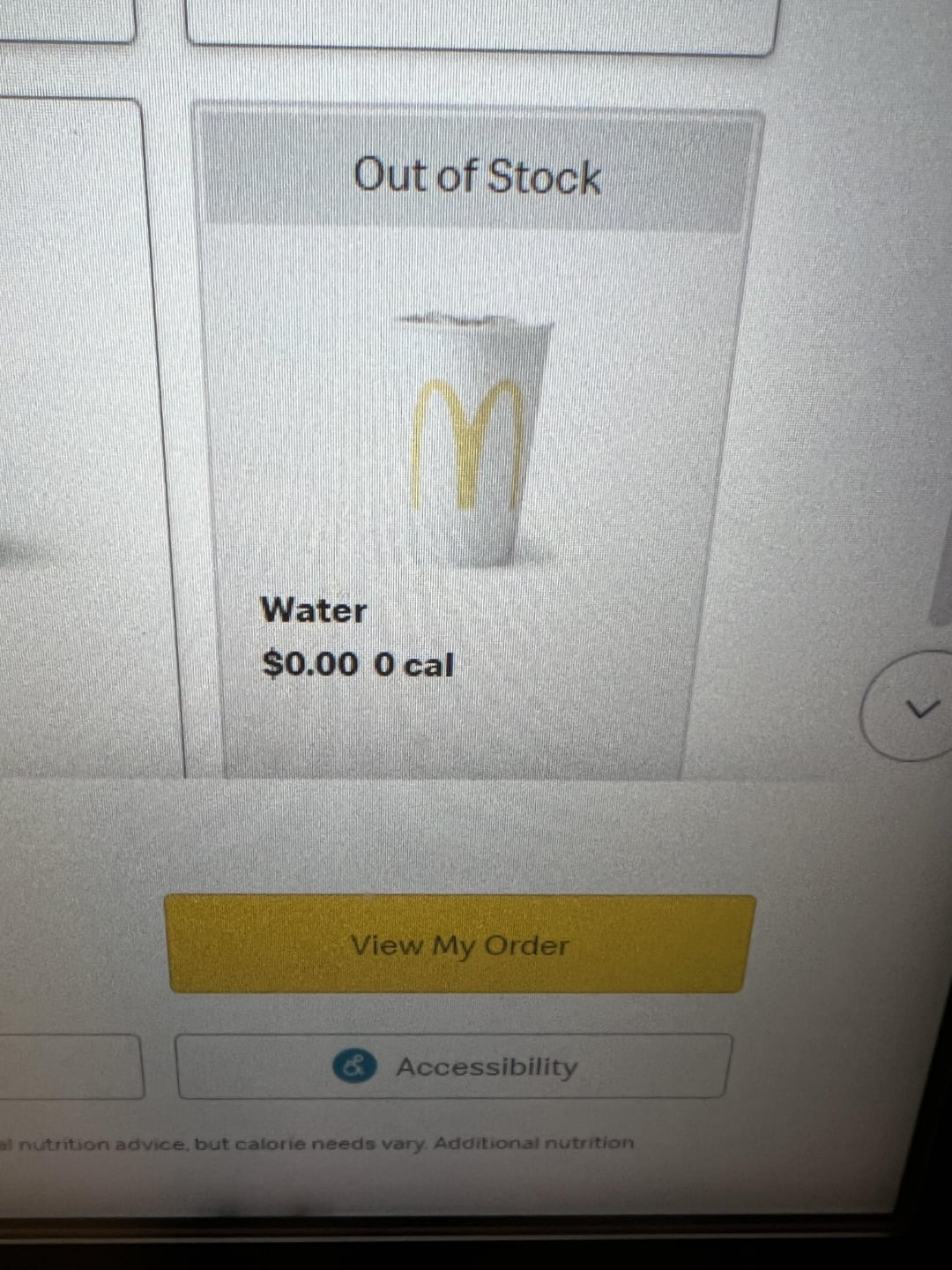 A McDonald's digital menu screen shows water as "Out of Stock," with a cup displaying the McDonald's logo, priced at $0.00 and 0 calories. Below are “View My Order” and “Accessibility” buttons.