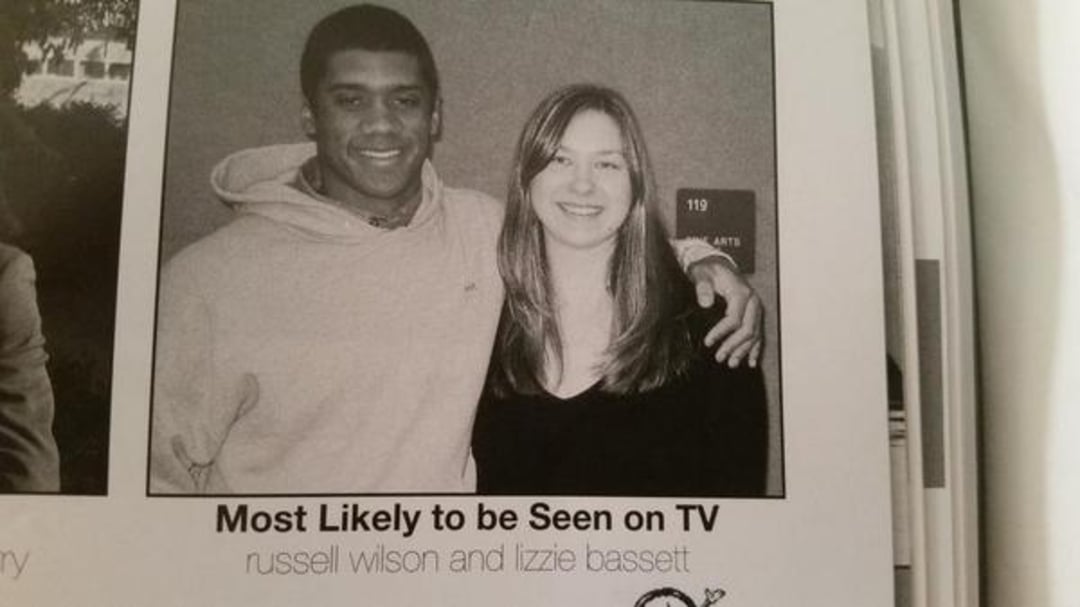 A young man and woman pose together, smiling, in a black-and-white yearbook photo. The caption reads, "Most Likely to be Seen on TV: russell wilson and lizzie bassett.
