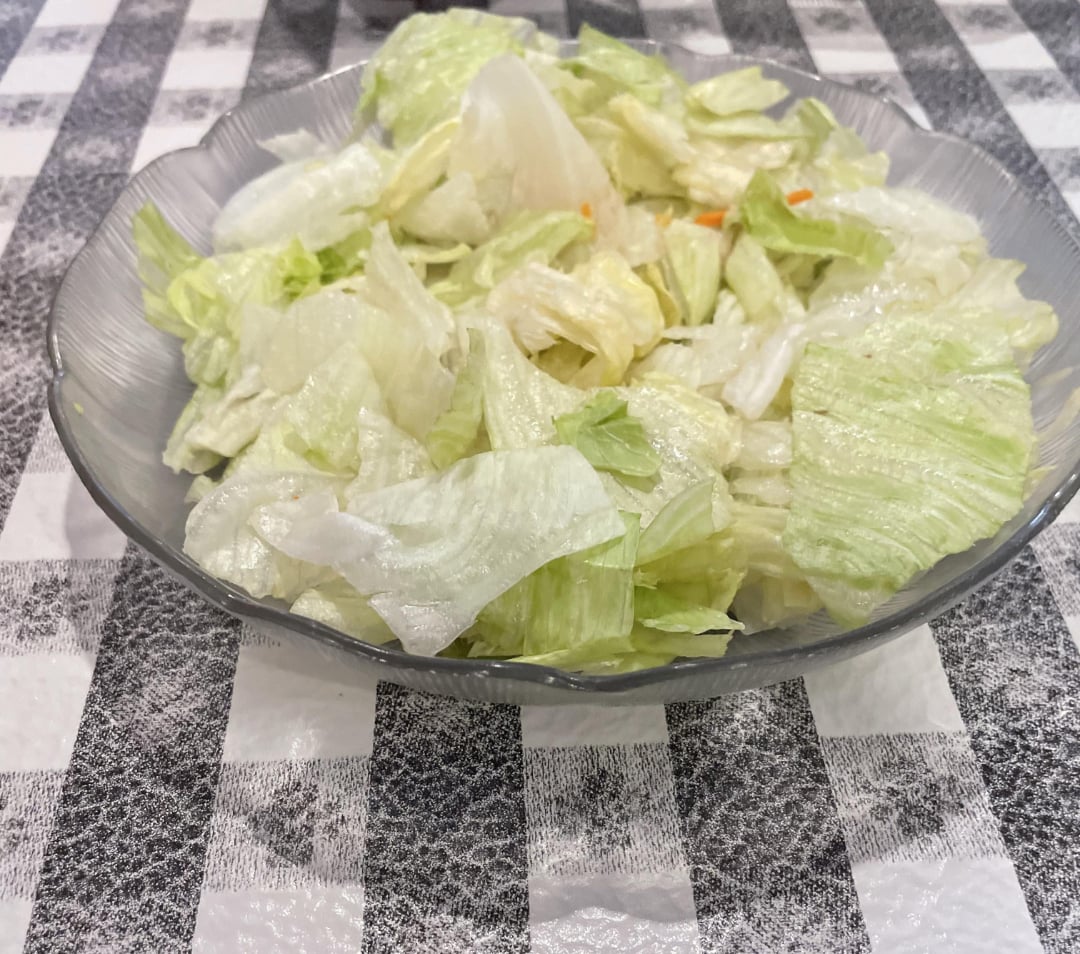 A clear glass plate filled with chopped iceberg lettuce sits on a black and white checkered tablecloth.