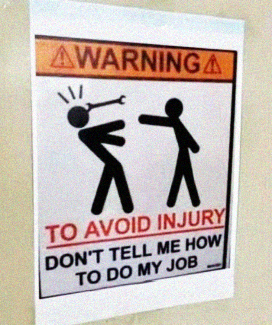 A humorous warning sign shows a stick figure hitting another with a wrench. Text: “WARNING: TO AVOID INJURY, DON’T TELL ME HOW TO DO MY JOB.”