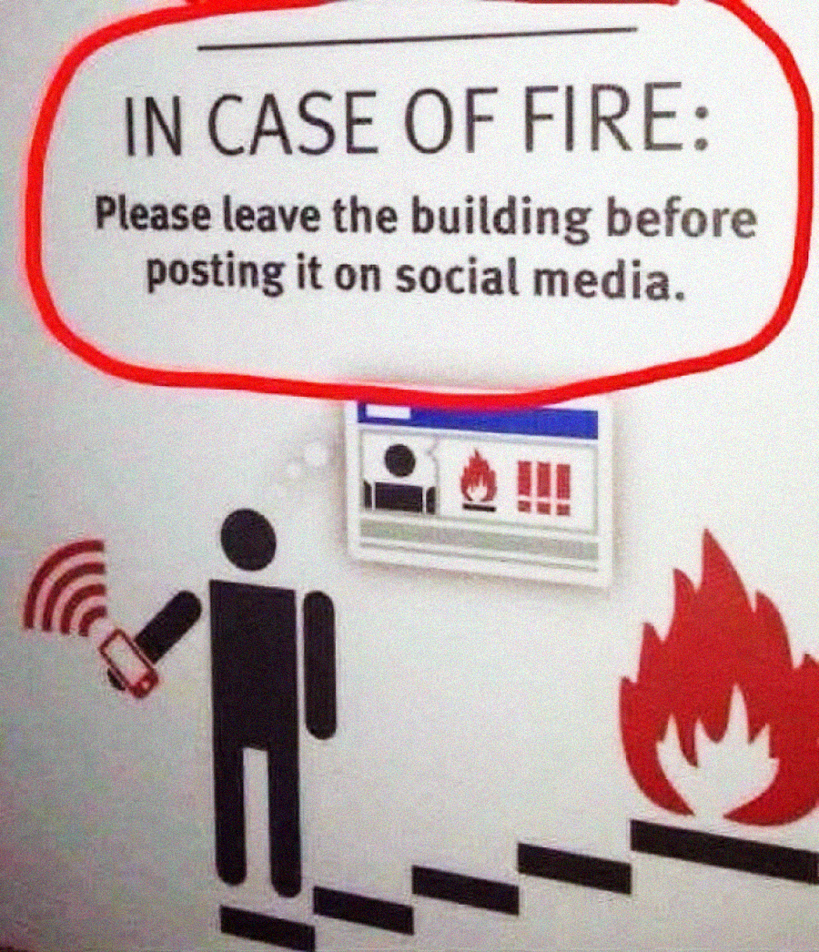 A humorous sign reads, "IN CASE OF FIRE: Please leave the building before posting it on social media." Below is an icon of a person holding a phone near flames and a staircase.