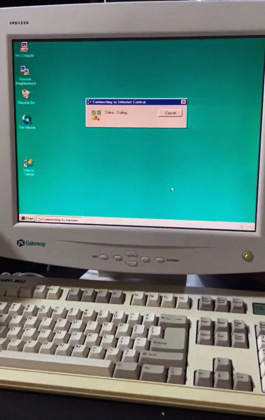 A vintage Gateway computer monitor and keyboard display a Windows 95 desktop with a pop-up window showing “Connecting to Internet” and classic desktop icons.