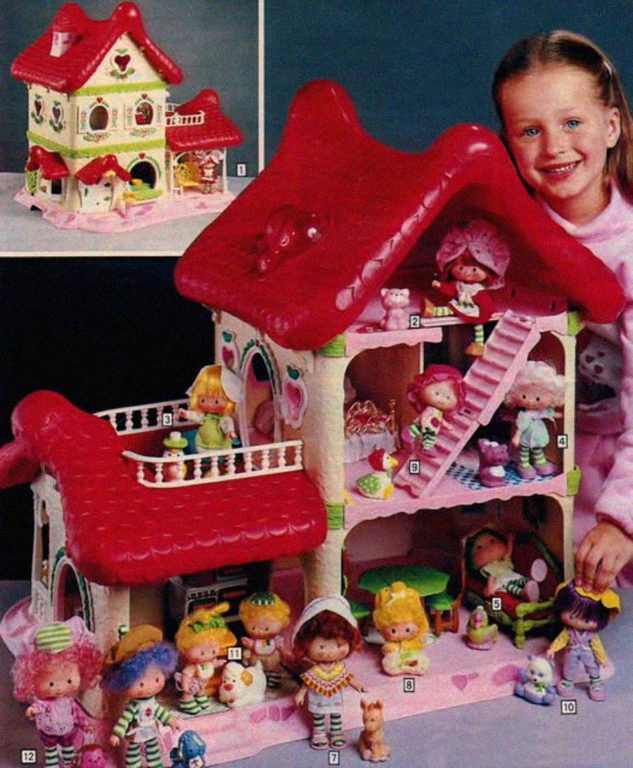 A smiling girl poses with a colorful Strawberry Shortcake dollhouse, featuring a red roof and several Strawberry Shortcake dolls and accessories arranged on two floors and outside the house. An inset shows a close-up of the dollhouse exterior.