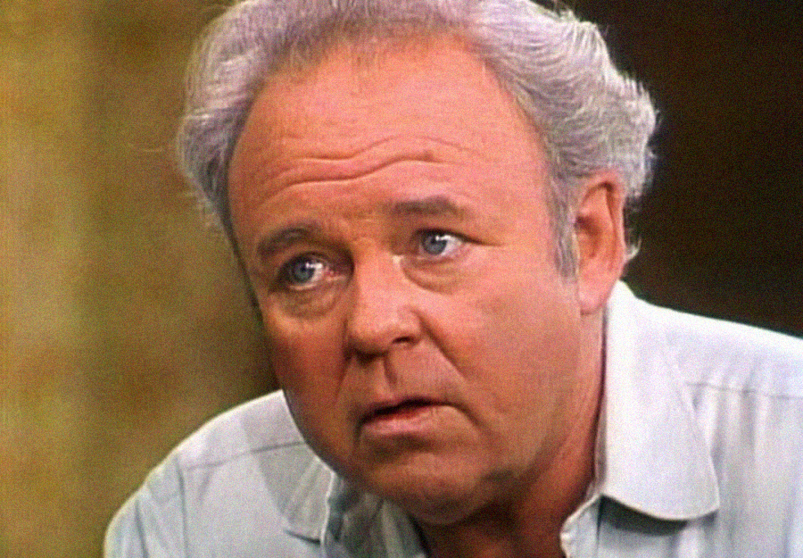 A middle-aged man with gray hair looks slightly upward with a serious, concerned expression. He is wearing a light-colored shirt and the background is blurred.