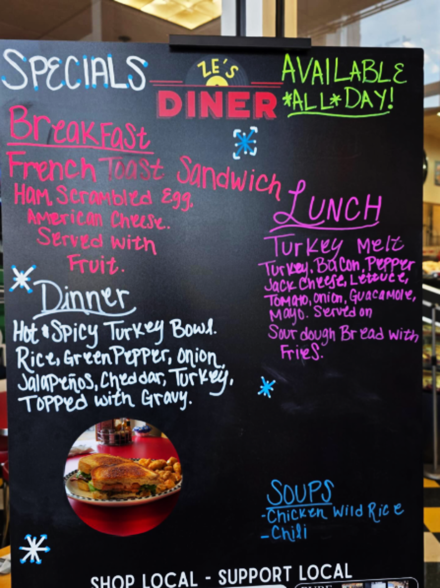 A chalkboard menu at Ze's Diner displays specials for breakfast, lunch, and dinner, including a French toast sandwich, turkey melt, hot turkey bowl, and soups. Colorful chalk highlights different sections.