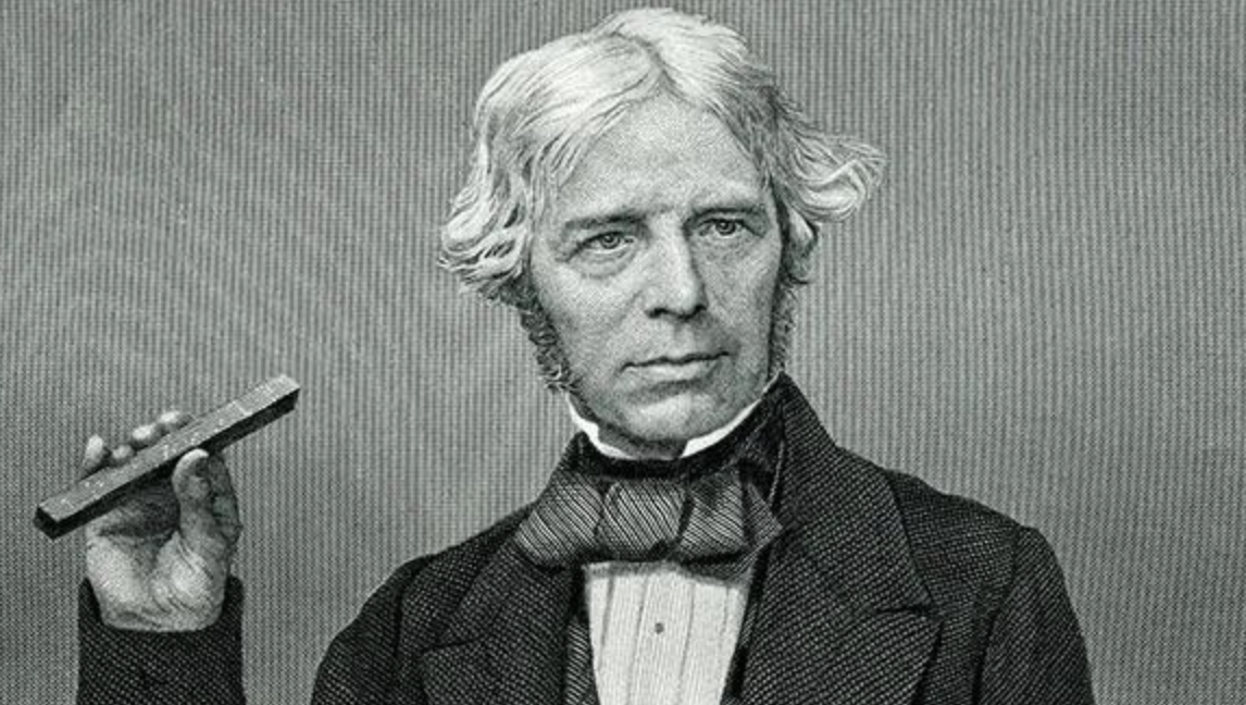 Black-and-white portrait of an older man with wavy hair, wearing a suit and bow tie, holding a rectangular object in his right hand, gazing directly at the viewer.