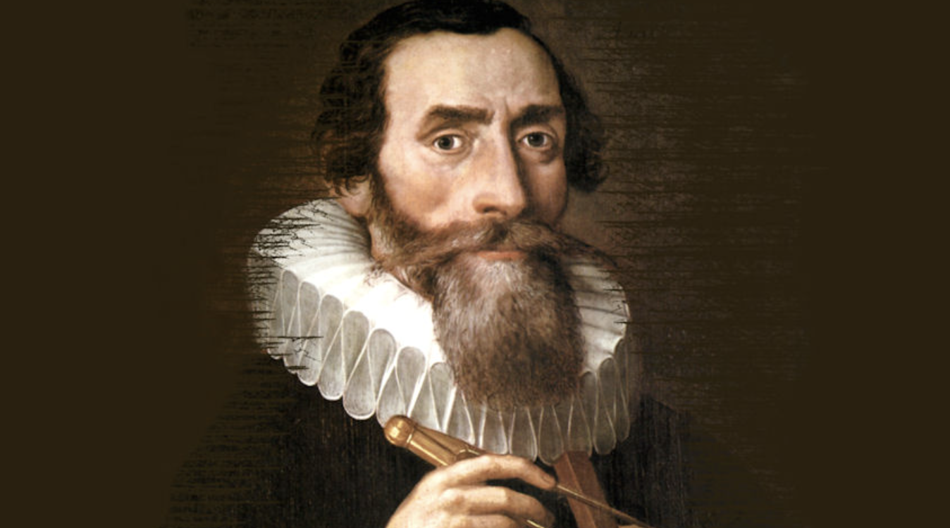 A bearded man with dark hair wearing a white ruffled collar and dark clothing, holding a small book or instrument against a brown background.