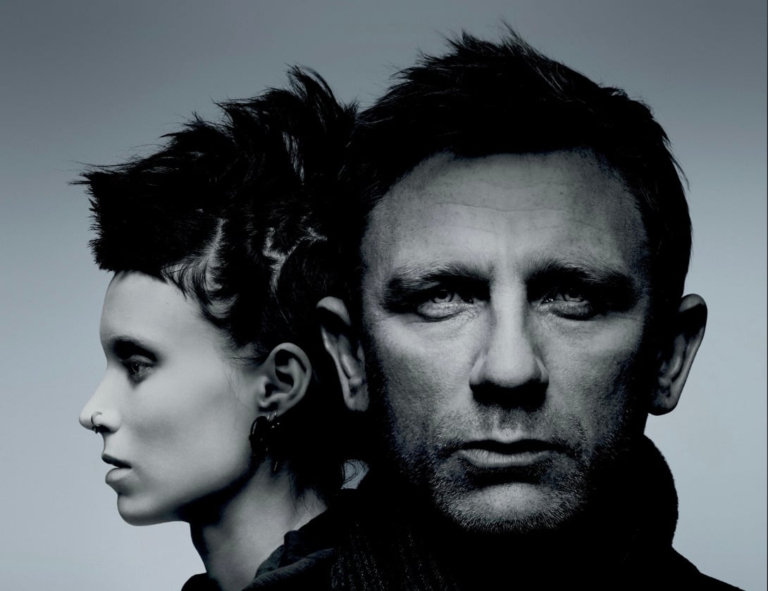 A black and white image of a man facing forward with a serious expression and a woman in profile beside him, her head turned to the left, both with dramatic lighting and sharp contrasts.