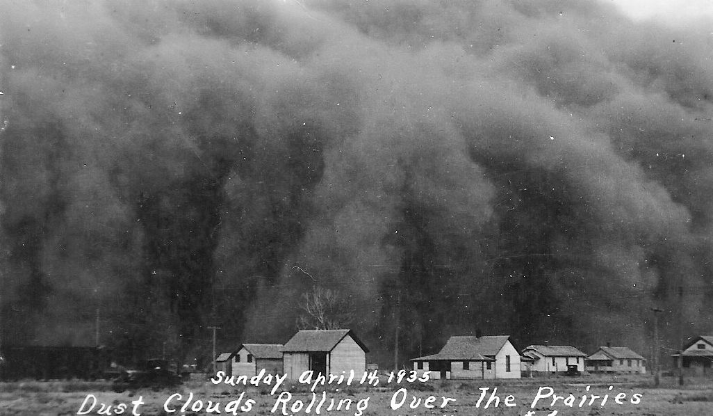 A massive dark dust cloud looms over small houses on a prairie. The text on the image reads, "Sunday April 14, 1935 Dust Clouds Rolling Over The Prairies.