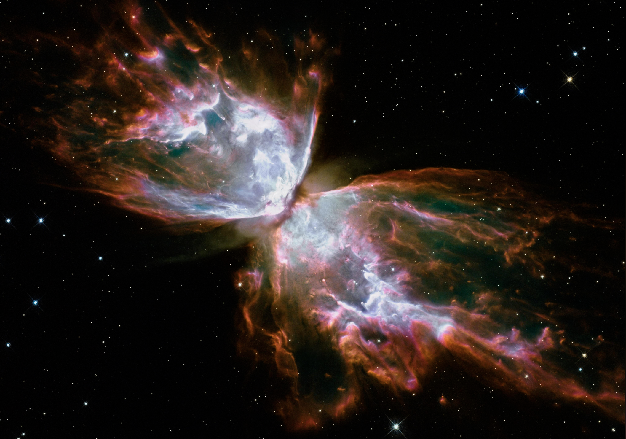 Colorful clouds of gas form butterfly-like wings in the Butterfly Nebula against a backdrop of stars in space, with glowing pink, orange, white, and green hues surrounding a bright center.