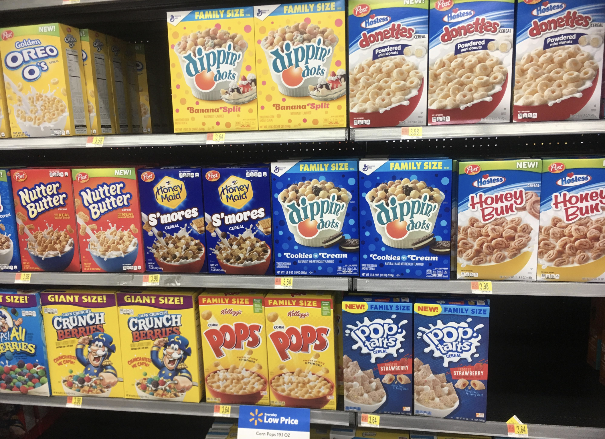 A supermarket cereal aisle displays colorful boxes, including Oreo O’s, Dippin’ Dots in various flavors, Nutter Butter, Honey Bun, Cap’n Crunch, Corn Pops, and Frosted Strawberry Pop-Tarts cereals.