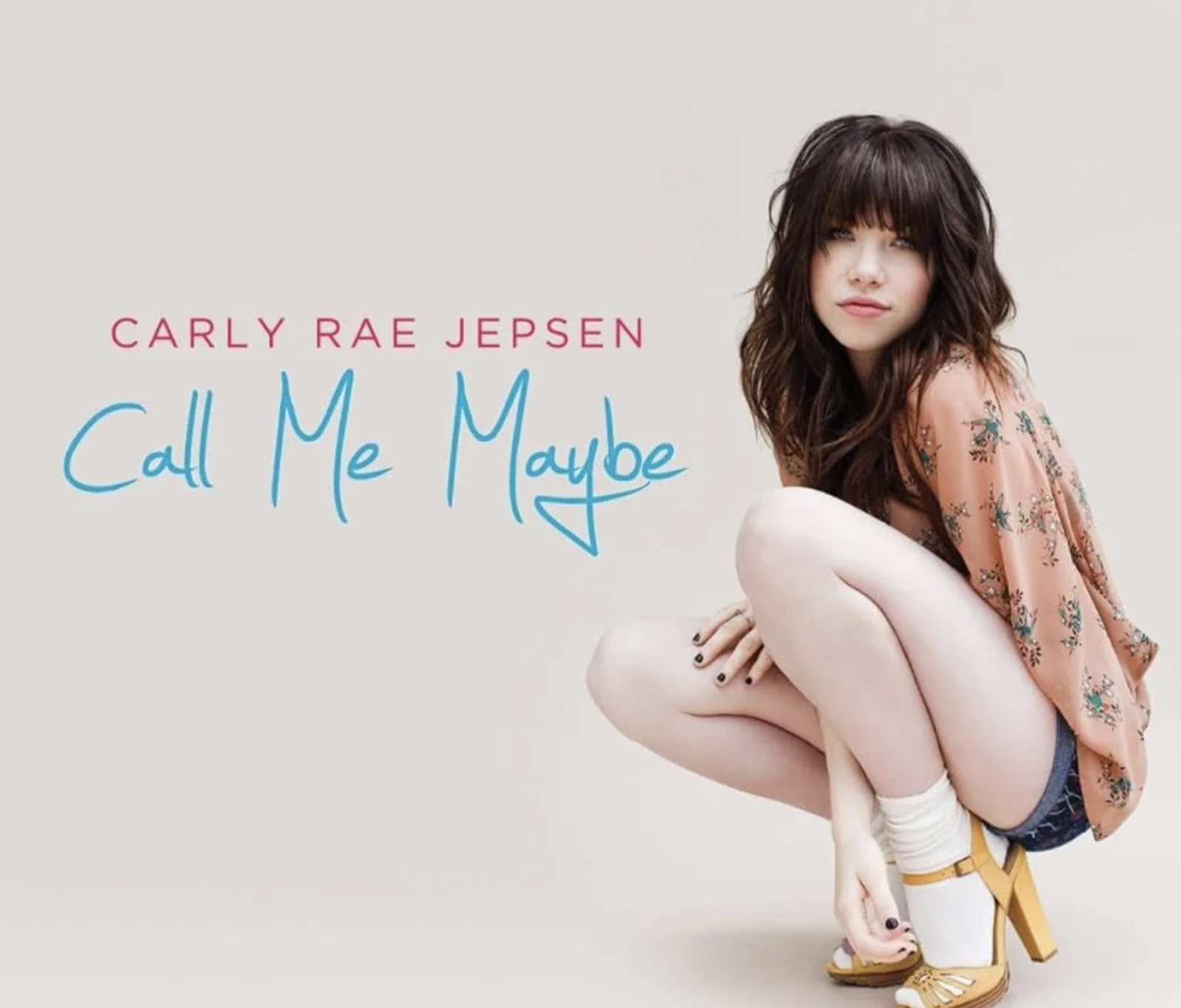 A woman with long dark hair squats while looking at the camera, wearing a peach floral top, white shorts, yellow heels, and white socks. The text reads "Carly Rae Jepsen Call Me Maybe" in coral and blue letters.