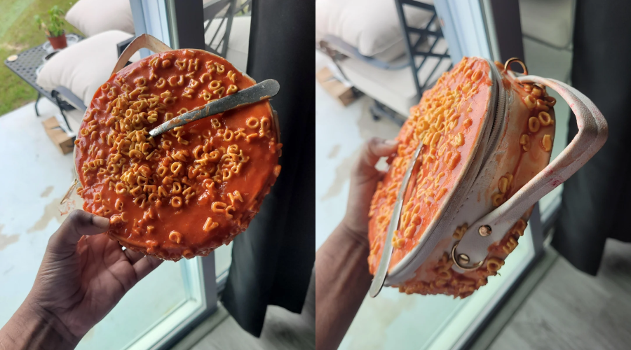 A realistic purse designed to look like a plate of SpaghettiOs with a spoon, shown from the top and side, being held in someone's hand near a window with patio furniture outside.