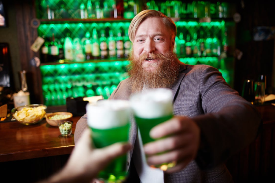 A man holding up two glasses of green liquid