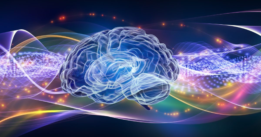 A glowing, semi-transparent brain is centered against a dark background with colorful light waves, sparkles, and gentle energy trails swirling around it, suggesting concepts of thought, creativity, or artificial intelligence.