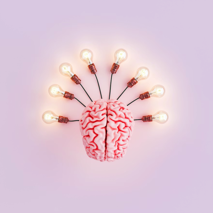 A model of a brain is positioned against a pastel background, with eight lit lightbulbs radiating outward from it, symbolizing creativity or ideas emerging from the mind.
