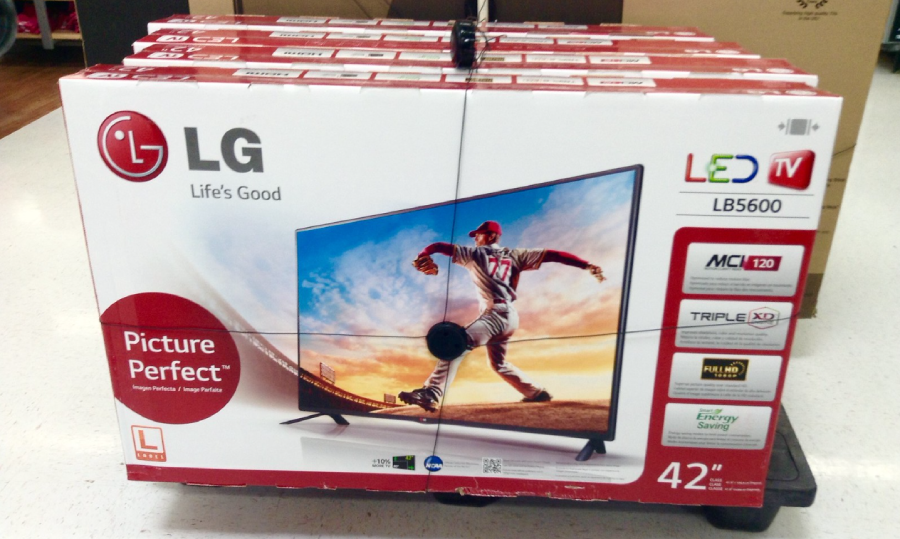 A boxed LG LED TV (model LB5600) on display, showing a baseball player pitching on screen. The box advertises features like "Picture Perfect," 42-inch size, Triple XD Engine, and Energy Saving.